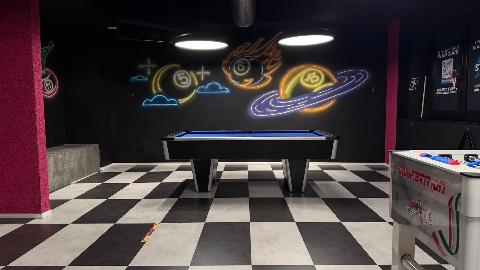 Interno della sala giochi D-Play con postazioni, cabinati e insegne al neon